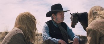 Movie still from “The Homesman” (2014), directed by Tommy Lee Jones – An old man sitting on the ground next to a horse; Close Up shot, Over the shoulder angle