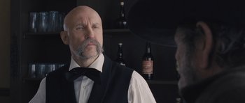 Movie still from “The Homesman” (2014), directed by Tommy Lee Jones – A man in a vest and a bow tie with a beard; Close Up shot, Low angle