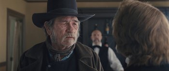 Movie still from “The Homesman” (2014), directed by Tommy Lee Jones – An old man wearing a black hat and a brown jacket; Close Up shot, Over the shoulder angle