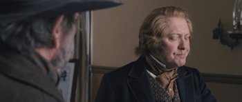 Movie still from “The Homesman” (2014), directed by Tommy Lee Jones – A man with long blonde hair wearing a suit and tie; Close Up shot, Over the shoulder angle