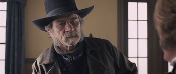 Movie still from “The Homesman” (2014), directed by Tommy Lee Jones – An older man wearing a black hat and a brown jacket; Close Up shot, Over the shoulder angle