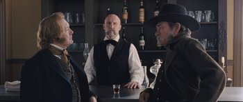 Movie still from “The Homesman” (2014), directed by Tommy Lee Jones – A group of men standing around a bar; Medium shot, Over the shoulder angle