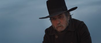 Movie still from “The Homesman” (2014), directed by Tommy Lee Jones – An older man wearing a black hat and a black coat; Close Up shot, Over the shoulder angle