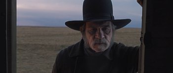 Movie still from “The Homesman” (2014), directed by Tommy Lee Jones – An old man with a black hat in the middle of a field; Close Up shot, Over the shoulder angle
