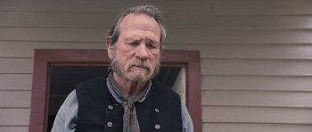 Movie still from “The Homesman” (2014), directed by Tommy Lee Jones – An older man wearing a vest and a neck tie; Close Up shot, Over the shoulder angle