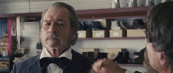 Movie still from “The Homesman” (2014), directed by Tommy Lee Jones – An older man in a suit and bow tie; Close Up shot, Over the shoulder angle