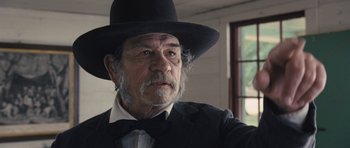 Movie still from “The Homesman” (2014), directed by Tommy Lee Jones – An older man wearing a black hat and a bow tie; Close Up shot, Over the shoulder angle