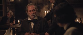 Movie still from “The Homesman” (2014), directed by Tommy Lee Jones – An older man in a suit and tie; Medium shot, Over the shoulder angle