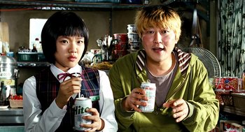 Movie still from “The Host” (2006), directed by Bong Joon Ho – Two people sitting next to each other holding cans of soda; Close Up shot, Low angle