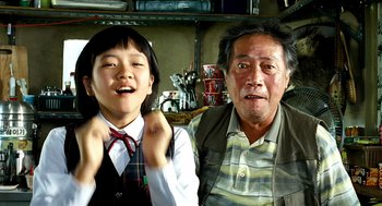 Movie still from “The Host” (2006), directed by Bong Joon Ho – An older man and a young girl posing for a picture; Close Up shot, Low angle