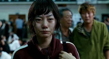 Movie still from “The Host” (2006), directed by Bong Joon Ho – A young woman is looking into the camera; Close Up shot, Over the shoulder angle