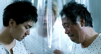 Movie still from “The Host” (2006), directed by Bong Joon Ho – Two men are talking to each other in front of a woman; Close Up shot, Over the shoulder angle