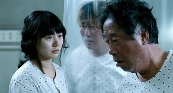 Movie still from “The Host” (2006), directed by Bong Joon Ho – A group of people standing next to each other in a room; Medium shot, Over the shoulder angle