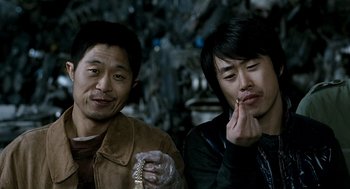 Movie still from “The Host” (2006), directed by Bong Joon Ho – Two asian men sitting next to each other; Close Up shot, Low angle