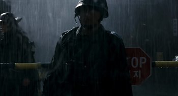 Movie still from “The Host” (2006), directed by Bong Joon Ho – A man wearing a helmet in the pouring rain; Medium shot, Low angle