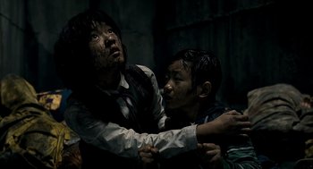 Movie still from “The Host” (2006), directed by Bong Joon Ho – Two people are holding each other in a dark room; Medium shot, Low angle