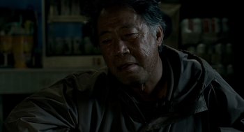 Movie still from “The Host” (2006), directed by Bong Joon Ho – An older man with blue hair is sitting in a room; Close Up shot, Over the shoulder angle