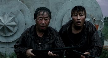Movie still from “The Host” (2006), directed by Bong Joon Ho – Two asian men in rain jackets holding guns; Medium shot, High angle