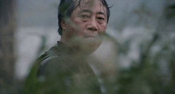 Movie still from “The Host” (2006), directed by Bong Joon Ho – An older asian man with wet hair looking at the camera; Close Up shot, Low angle