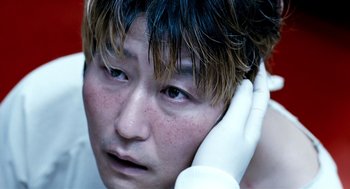 Movie still from “The Host” (2006), directed by Bong Joon Ho – A person with a hand on their ear; Close Up shot, Low angle
