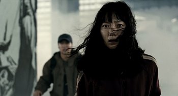 Movie still from “The Host” (2006), directed by Bong Joon Ho – A woman with long black hair and a man in a black jacket; Close Up shot, Low angle