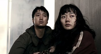 Movie still from “The Host” (2006), directed by Bong Joon Ho – A man and a woman standing next to each other; Close Up shot, Low angle