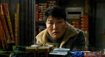 Movie still from “The Host” (2006), directed by Bong Joon Ho – A man sitting in front of a table of food; Close Up shot, Low angle