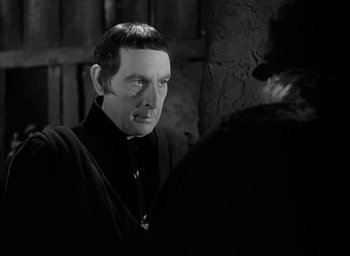 Movie still from “The Hunchback of Notre Dame” (1939), directed by William Dieterle – A black and white photo of a man in a priest's outfit; Close Up shot, Over the shoulder angle