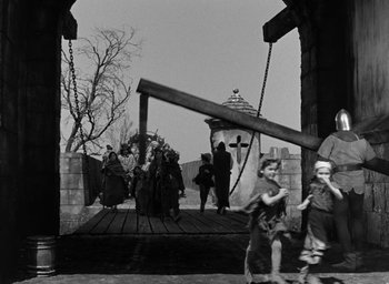 Movie still from “The Hunchback of Notre Dame” (1939), directed by William Dieterle – A black and white photo of people walking on a bridge; Wide shot, Low angle