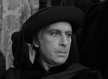 Movie still from “The Hunchback of Notre Dame” (1939), directed by William Dieterle – A black and white photo of a man wearing a hat; Close Up shot, High angle