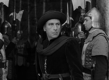 Movie still from “The Hunchback of Notre Dame” (1939), directed by William Dieterle – A black and white photo of a man in medieval garb; Medium shot, Over the shoulder angle