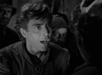 Movie still from “The Hunchback of Notre Dame” (1939), directed by William Dieterle – A man with a beard and a mustache is smoking a cigarette in front of other people; Close Up shot, Over the shoulder angle