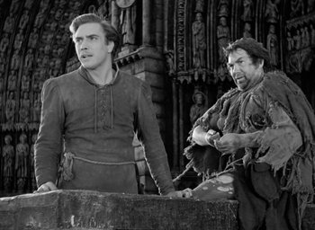 Movie still from “The Hunchback of Notre Dame” (1939), directed by William Dieterle – Two men in medieval garb standing next to each other; Medium shot, Low angle
