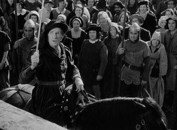 Movie still from “The Hunchback of Notre Dame” (1939), directed by William Dieterle – An old woman riding a horse in front of a group of people; Medium shot, High angle