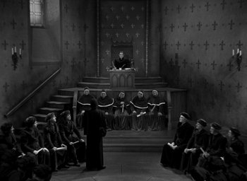 Movie still from “The Hunchback of Notre Dame” (1939), directed by William Dieterle – A group of people sitting in front of a priest; Extreme Wide shot, High angle