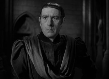 Movie still from “The Hunchback of Notre Dame” (1939), directed by William Dieterle – A black and white photo of a man in a robe; Close Up shot, Over the shoulder angle