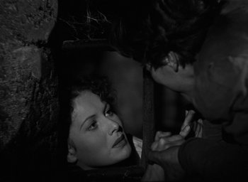 Movie still from “The Hunchback of Notre Dame” (1939), directed by William Dieterle – A man and a woman looking at each other through an opening in the wall; Close Up shot, Over the shoulder angle