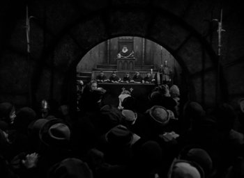 Movie still from “The Hunchback of Notre Dame” (1939), directed by William Dieterle – A group of people sitting in front of an audience; Wide shot, High angle