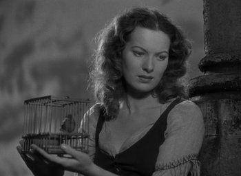 Movie still from “The Hunchback of Notre Dame” (1939), directed by William Dieterle – A black and white photo of a woman holding a bird in a birdcage; Close Up shot, Low angle