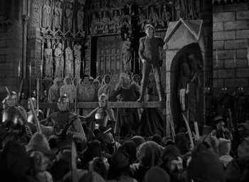 Movie still from “The Hunchback of Notre Dame” (1939), directed by William Dieterle – A group of people sitting in front of a building; Wide shot, High angle