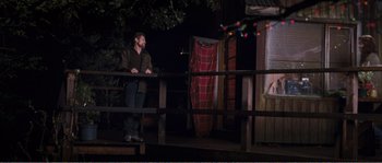 Movie still from “The Hunter” (2011), directed by Daniel Nettheim – A man standing on top of a wooden railing next to a tree; Wide shot, Low angle