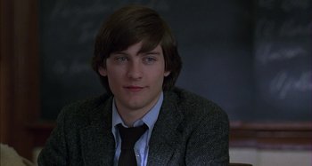 Movie still from “The Ice Storm” (1997), directed by Ang Lee – A man in a suit and tie sitting in front of a chalkboard; Close Up shot, Low angle