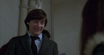 Movie still from “The Ice Storm” (1997), directed by Ang Lee – A man in a suit and tie smiling for the camera; Medium shot, Low angle