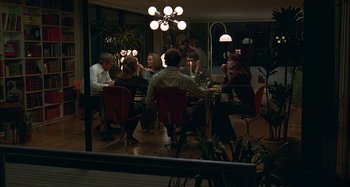 Movie still from “The Ice Storm” (1997), directed by Ang Lee – A group of people sitting around a table at night; Wide shot, High angle