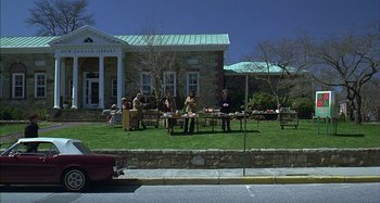 Movie still from “The Ice Storm” (1997), directed by Ang Lee – A group of people sitting around a table in the grass; Extreme Wide shot, High angle