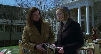 Movie still from “The Ice Storm” (1997), directed by Ang Lee – Two people standing next to each other and one is holding a book; Medium shot, Low angle