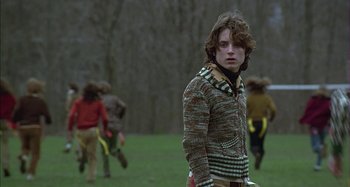 Movie still from “The Ice Storm” (1997), directed by Ang Lee – A young man standing in a field with a bunch of other young men; Medium shot, Over the shoulder angle