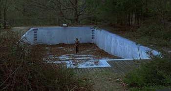 Movie still from “The Ice Storm” (1997), directed by Ang Lee – A person standing in front of an empty swimming pool; Extreme Wide shot, High angle