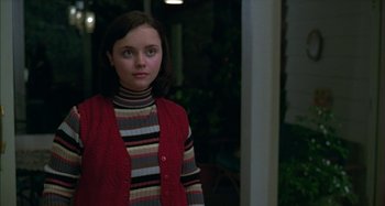 Movie still from “The Ice Storm” (1997), directed by Ang Lee – A young girl wearing a striped shirt and a red vest; Medium shot, Over the shoulder angle