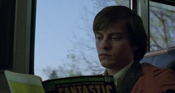 Movie still from “The Ice Storm” (1997), directed by Ang Lee – A man reading a comic book while sitting in a bus; Close Up shot, Over the shoulder angle
